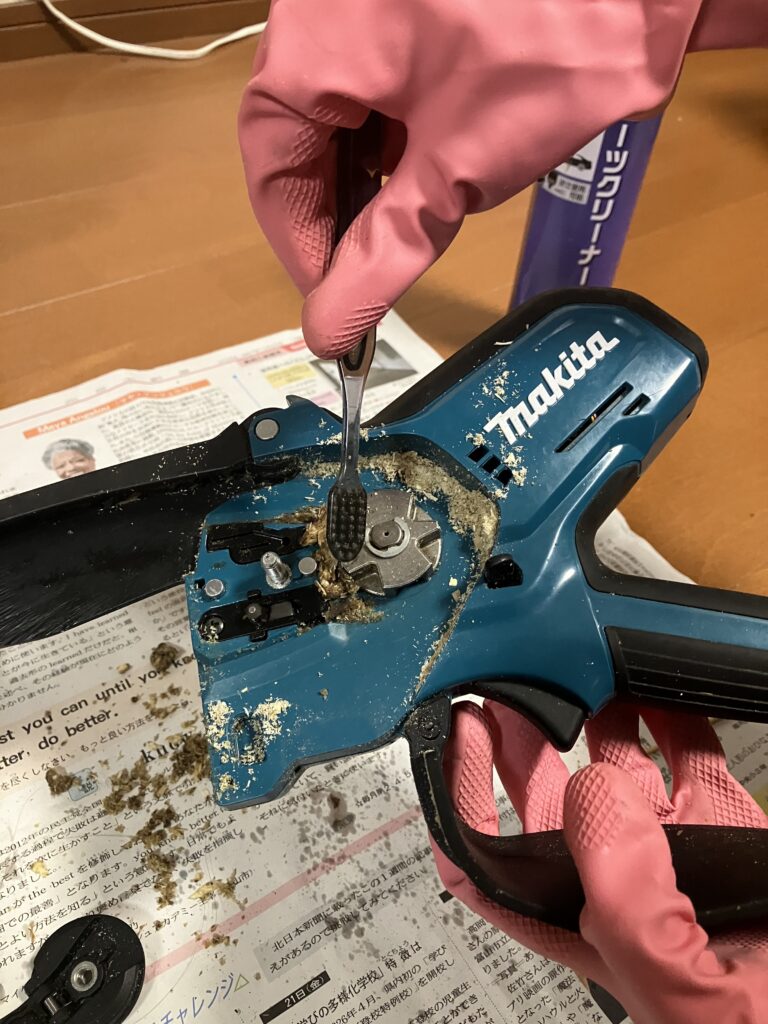 使用後のチェーンソーをブラシで掃除する様子。
