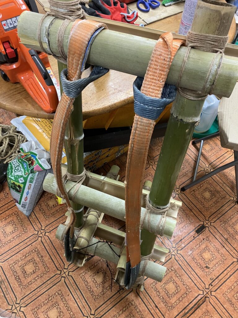 背負子(しょいこ)にスリングベルトを取り付けて背負えるように調整している工程