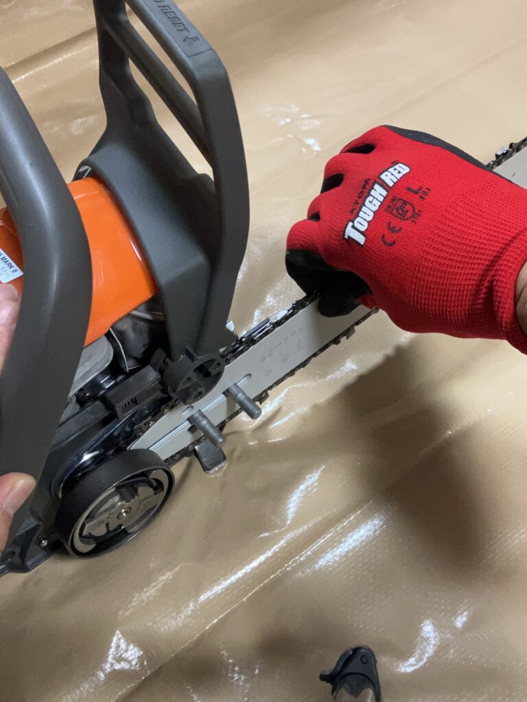 ハスクバーナ135MarkⅡでガイドバーに取り付けたチェーンの張り具合を軽く引っ張って調整しているところ。チェーンがたるまないよう確認する様子。