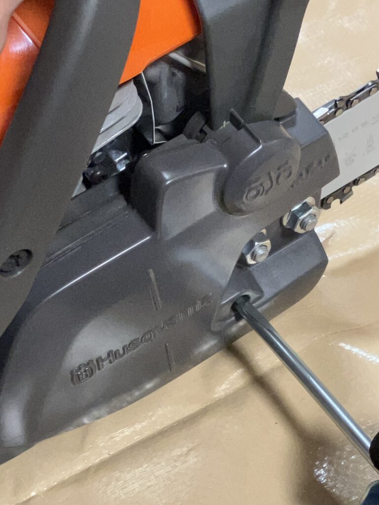 ハスクバーナ135MarkⅡのチェーンソーで、付属のレンチを使ってチェーンのテンションを手動で調整している様子。