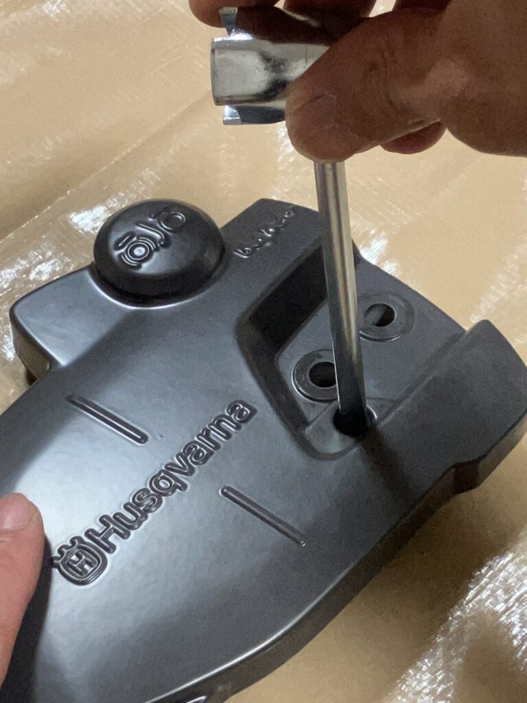 付属レンチでハスクバーナ135MarkⅡのチェーンテンション用突起部を右端まで調整している写真。