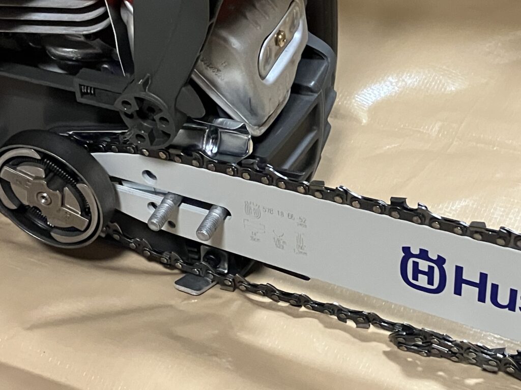 ハスクバーナ135MarkⅡのガイドバーにソーチェーンをはめ込む作業。チェーンの向きを確認しながらバーの溝に丁寧に装着している様子。
