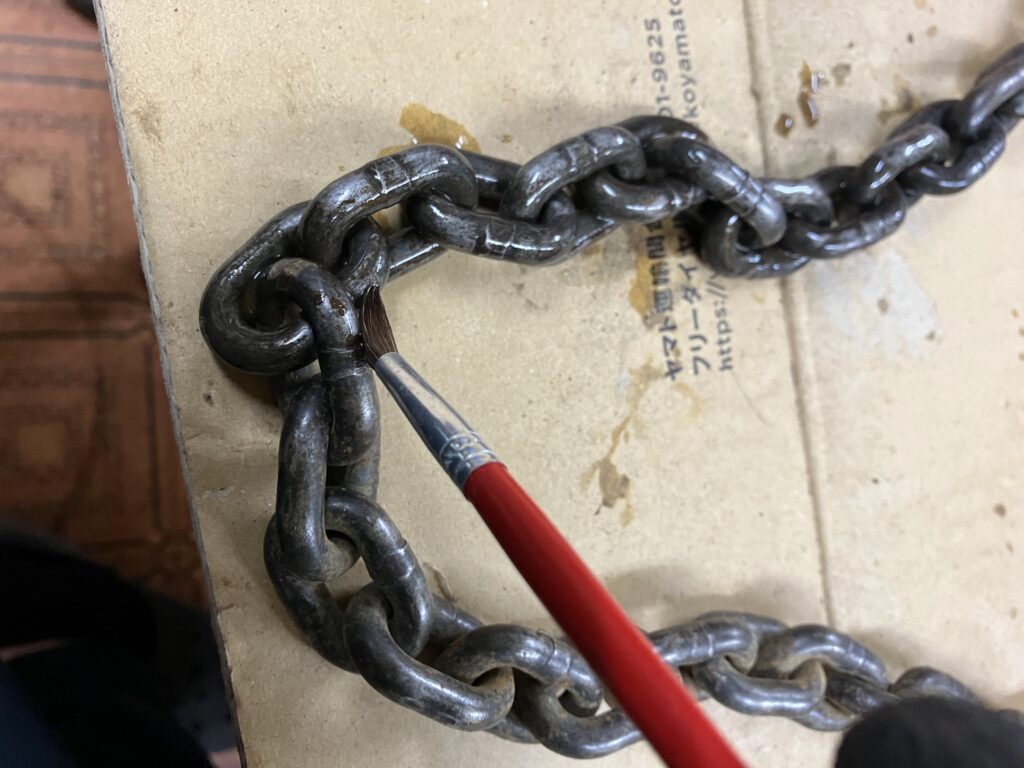 ラストリムーバーをレバーホイストの錆びたチェーンに塗布している作業中の様子。