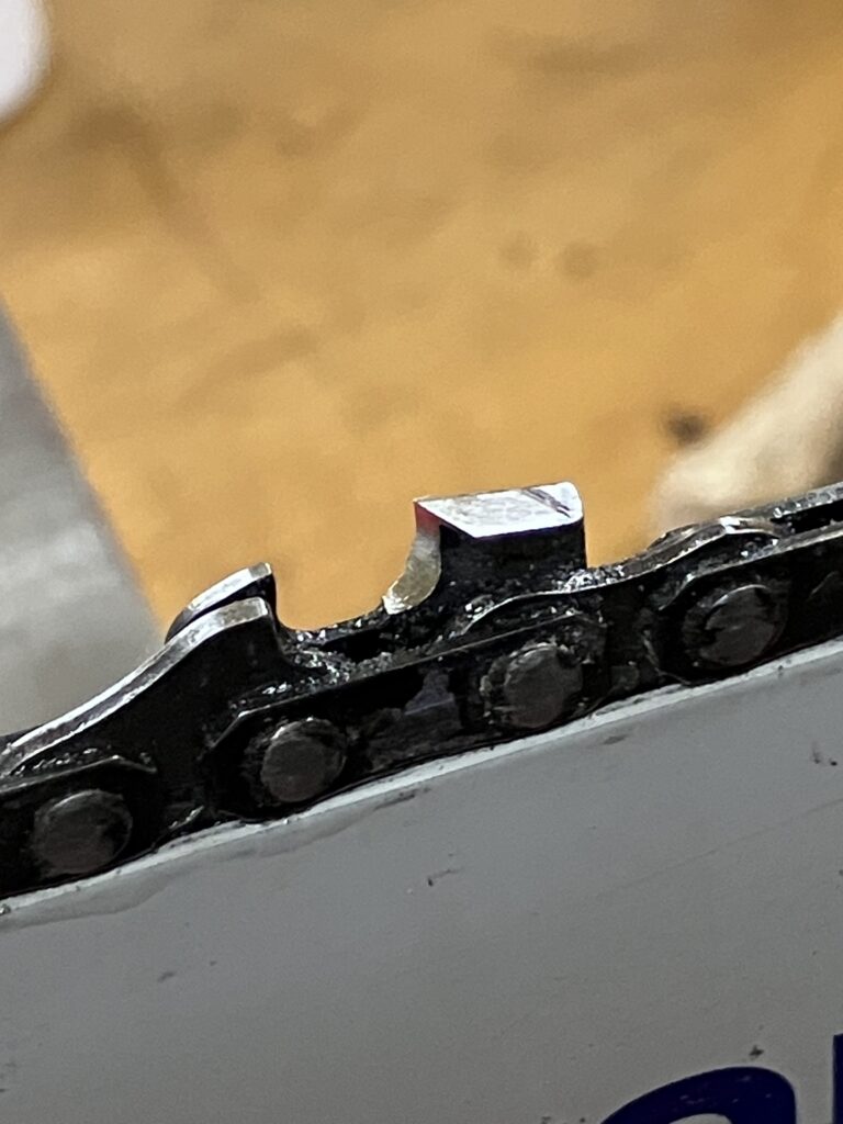 目立て後のチェーンソー刃。黒いマジックが削れ、金属光沢が見える研ぎ上がりの状態。