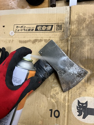 パーツクリーナーで斧の表面汚れを落としている作業中の写真。