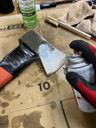 仕上げにKURE 5-56を斧に吹きかけ、防錆処理をしている写真。