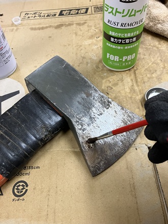 錆びた斧の刃にラストリムーバーを原液で塗っている作業中の写真。