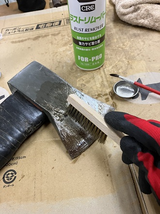 真鍮ブラシを使って斧の表面の錆を擦り落としている様子。