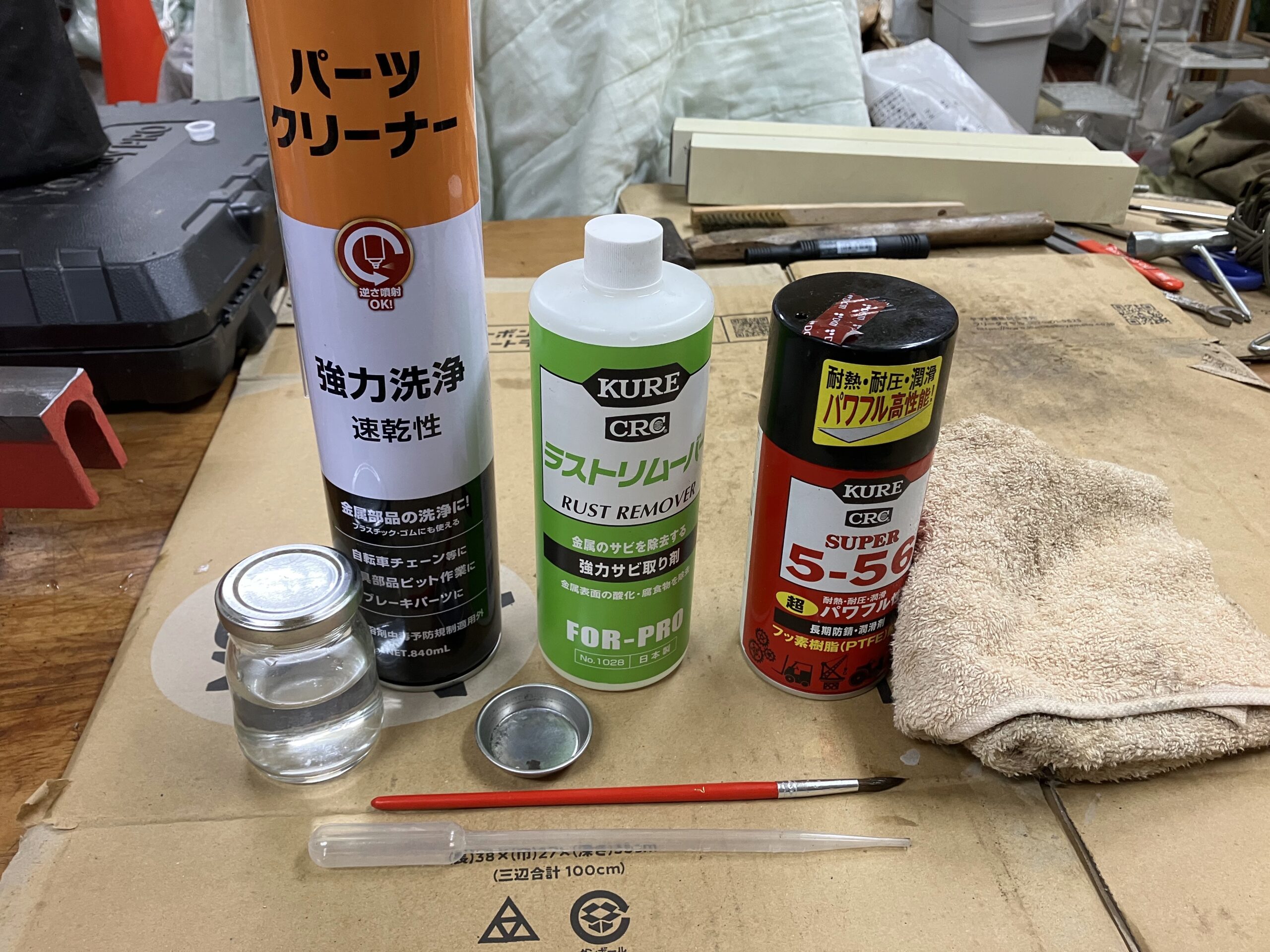 斧の錆び取りに使用する道具一式。ラストリムーバー、KURE 5-56、真鍮ブラシなどを並べた写真。