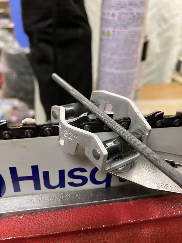 マジックで印をつけたチェーンソー刃を目立てキットで研いでいる様子。