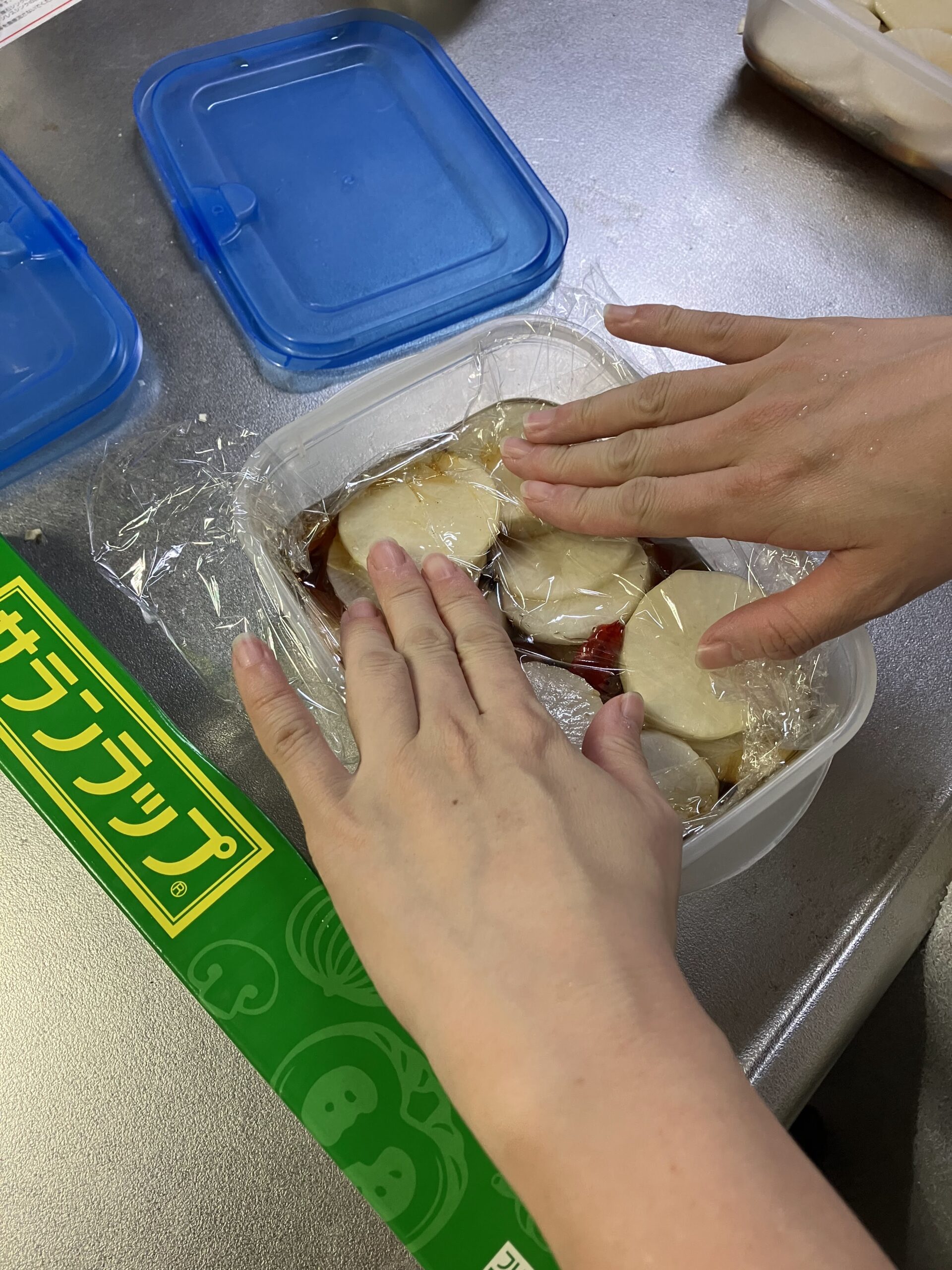 大根の甘辛醤油漬けにラップで押し蓋をして味を染み込ませている様子
