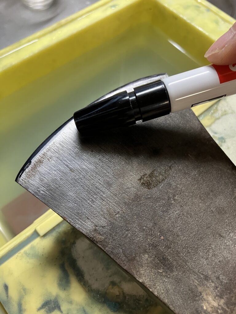 研ぐ角度を把握するために斧の刃にマジックで印をつけている写真