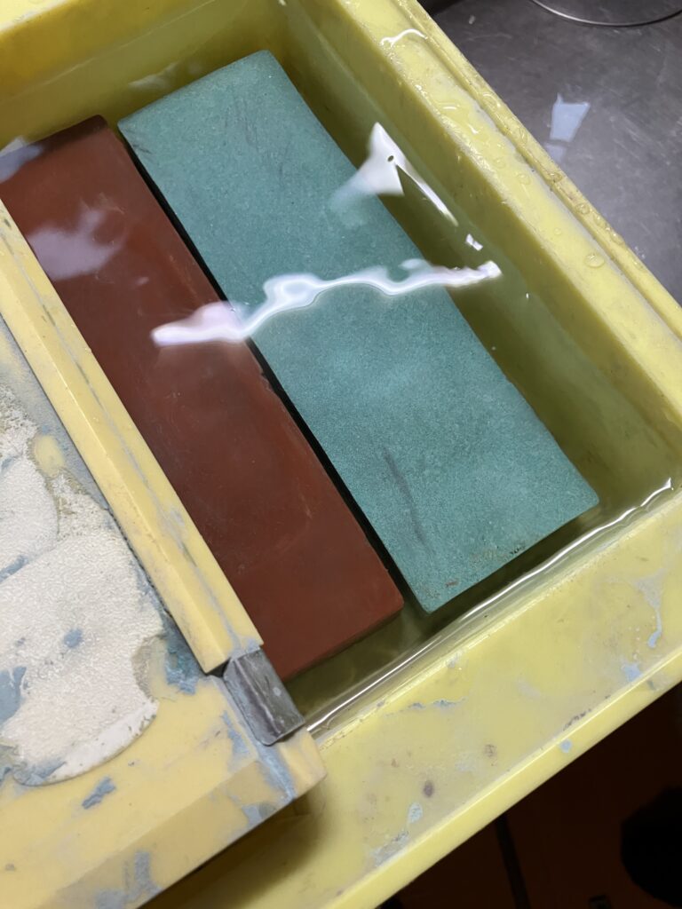斧を研ぐために砥石を水に浸して吸水させている写真