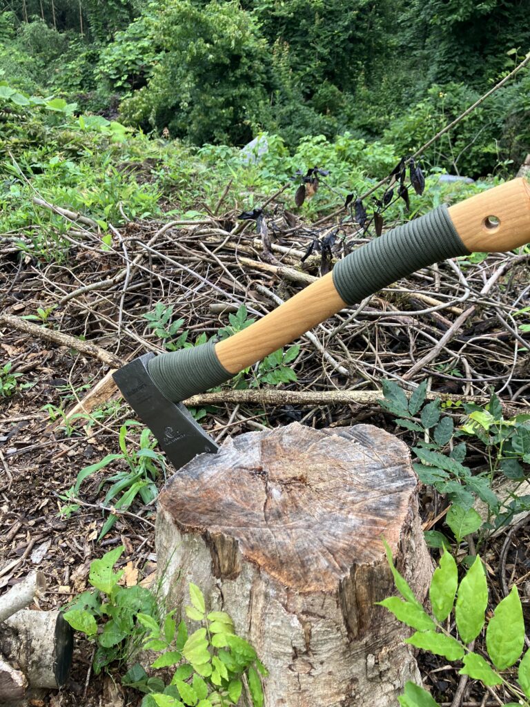 パラコードを巻いてカスタムした斧を切り株に刺した様子。滑り止めと携行性を高めた実用的な斧カスタム