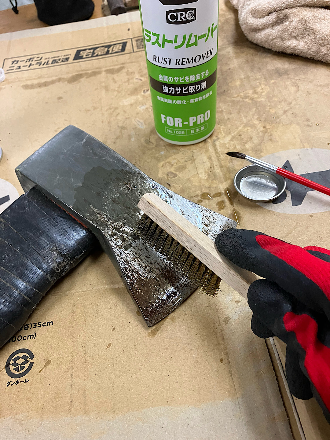 ラストリムーバーと真鍮ブラシを使って斧のサビを落としている作業風景