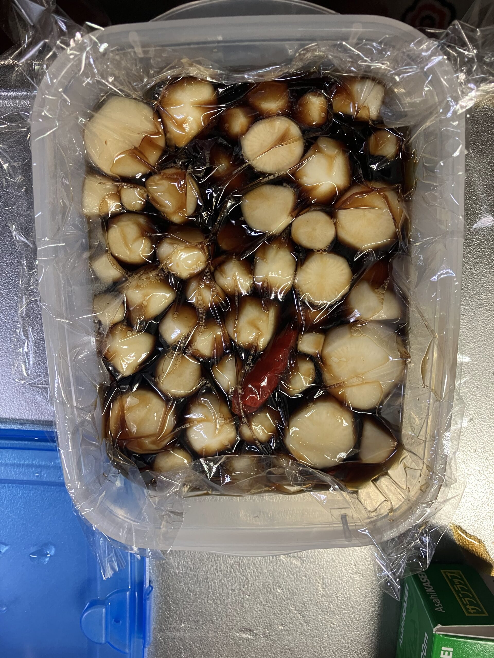 間引きカブと甘辛醤油ダレを合わせラップで押し蓋をしている様子