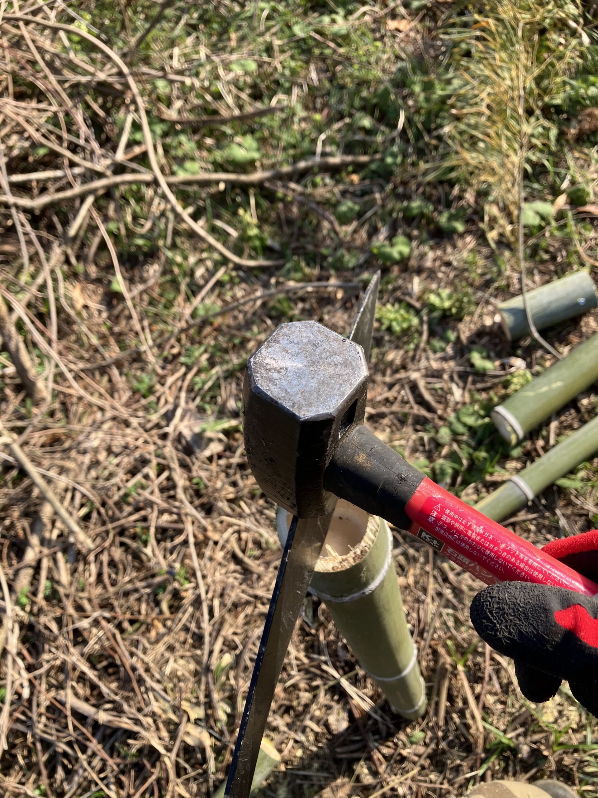 竹をククリナイフで半分に割っている作業