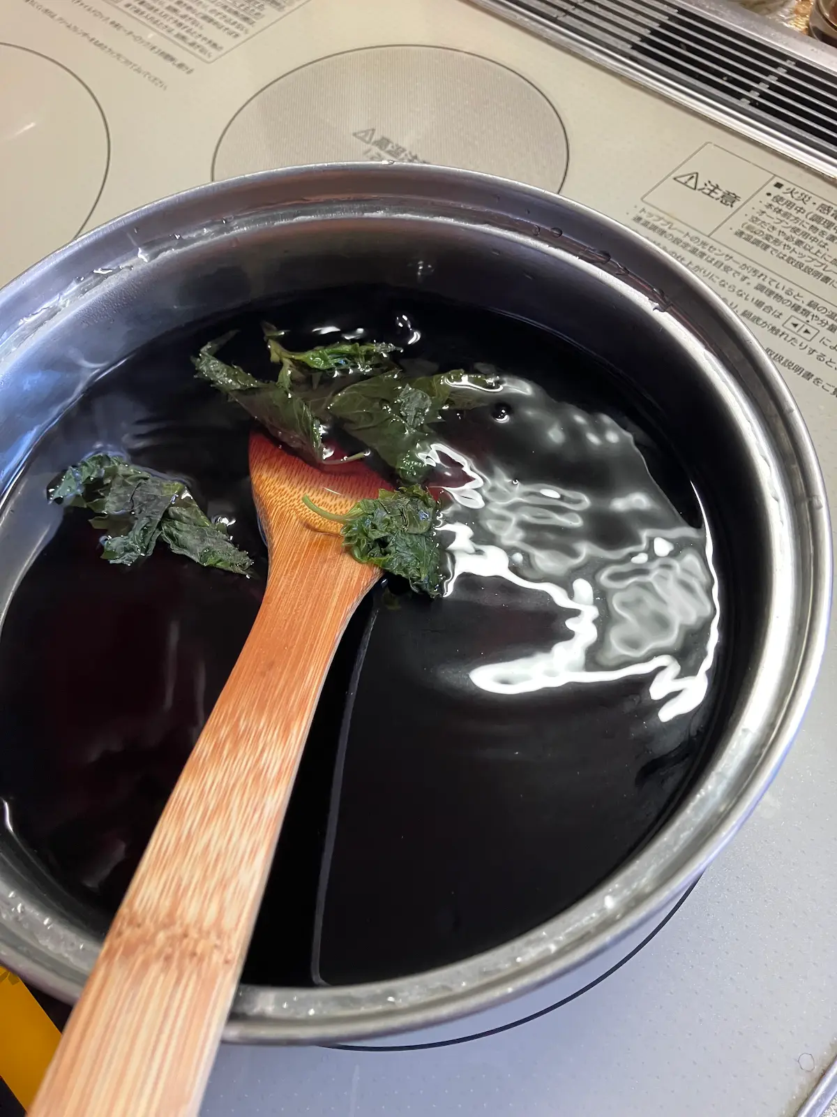 煮汁を作った赤シソの葉を数枚鍋に戻している様子