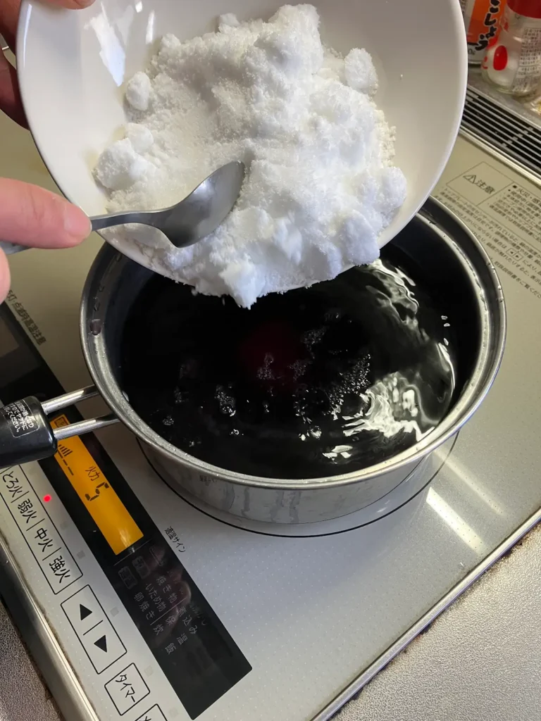 赤シソの煮汁に砂糖を加えて溶かしている様子