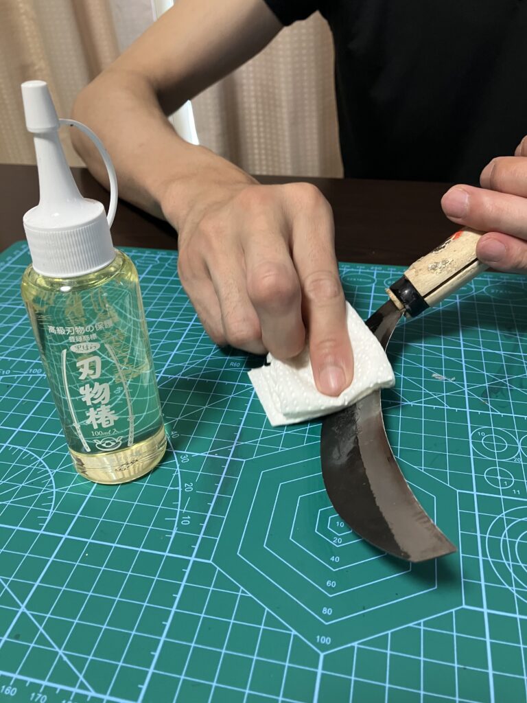 椿油を草刈り鎌の刃に塗って錆止めしている様子