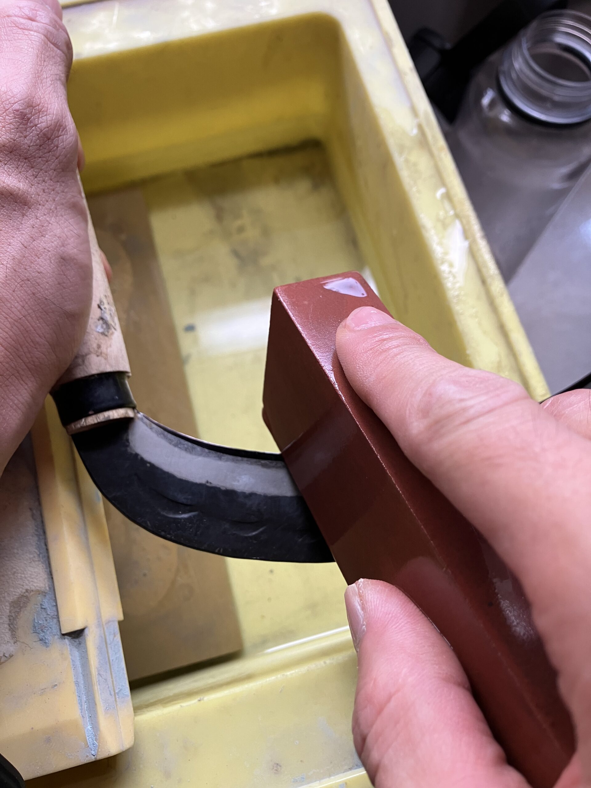 砥石を使って草刈り鎌を研いでいる様子