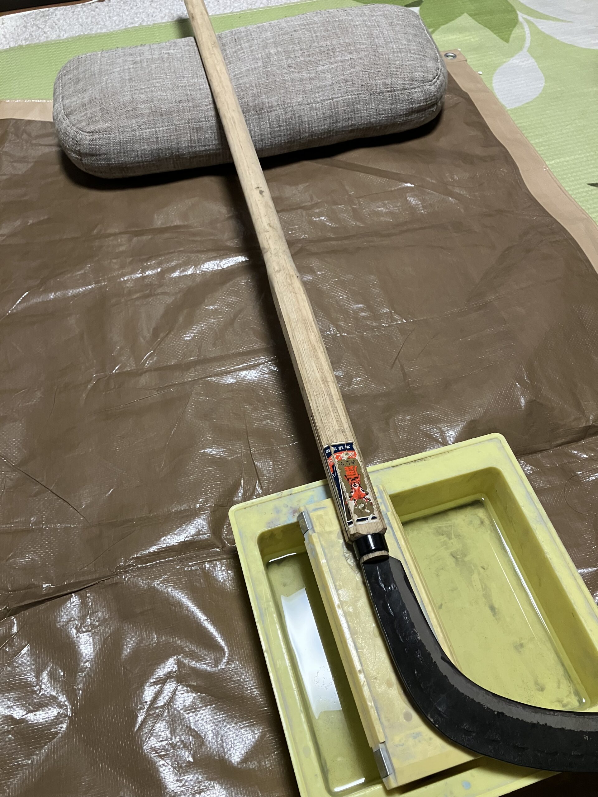 大鎌の刃を台に固定して研ぐ準備をしている様子